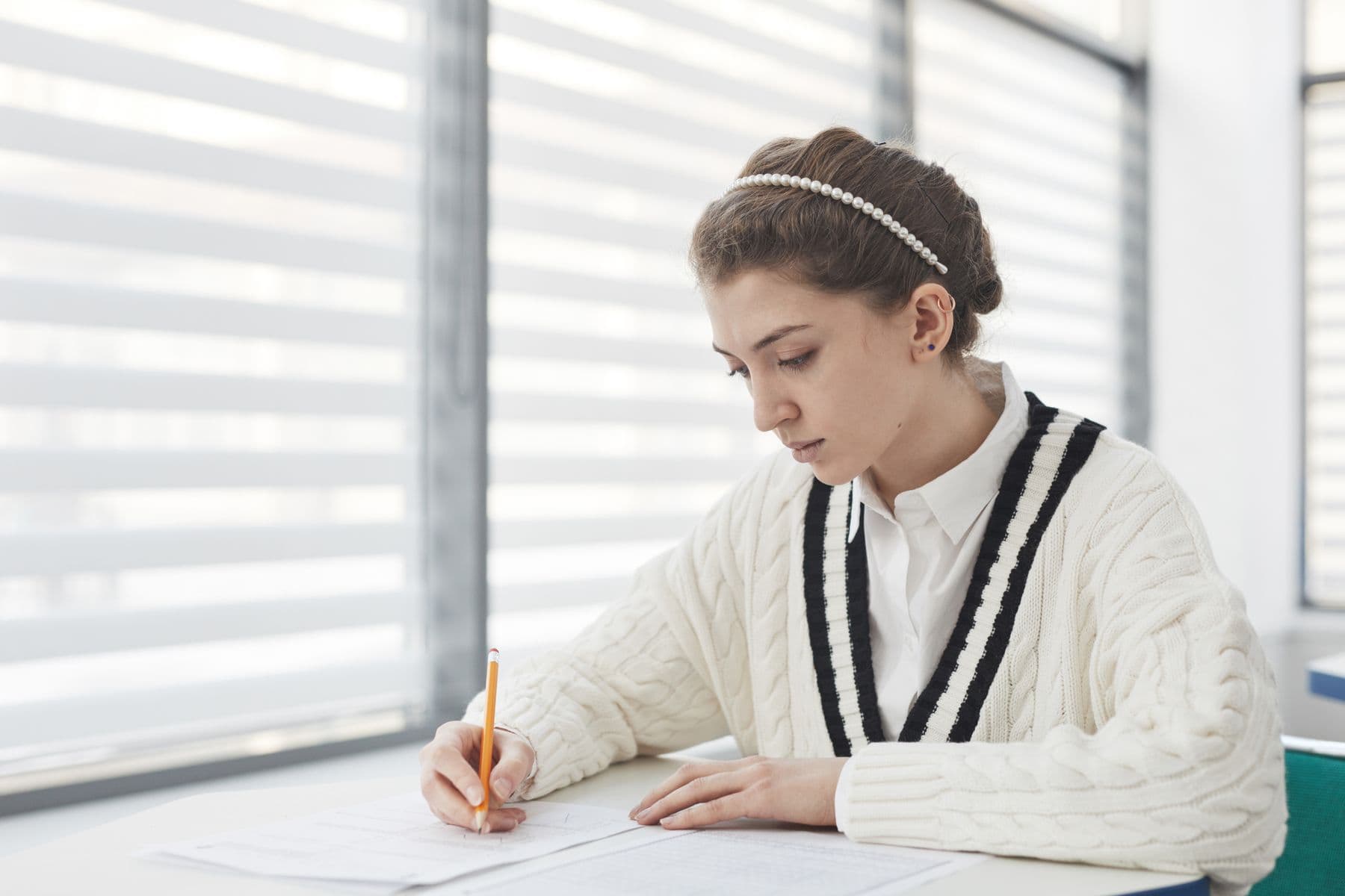 A student writing an essay by hand at a desk